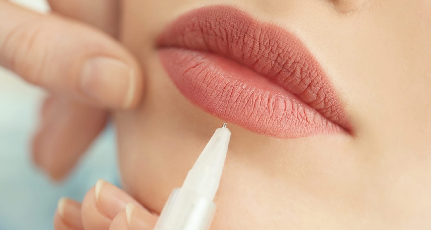 Young woman having permanent makeup on lips in beautician salon, closeup